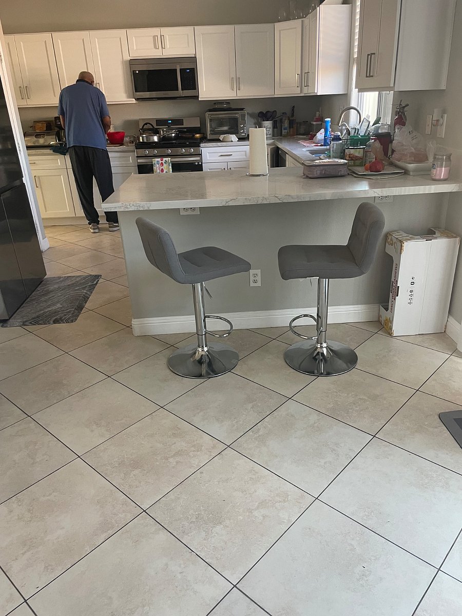Kitchen view with two seats over counter are two seats while others are in the kitchen, cooking or prepping food