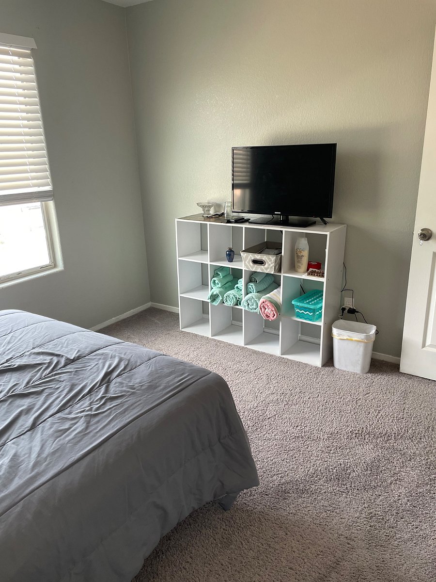 Another view of bedroom number two with TV, bookshelf, tiles and other amenities for the bathroom