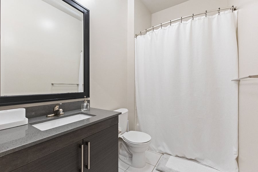 Large bathroom, equipped with sets of towels and starter items (toilet paper, travel size shampoo/conditioner, hand soap).