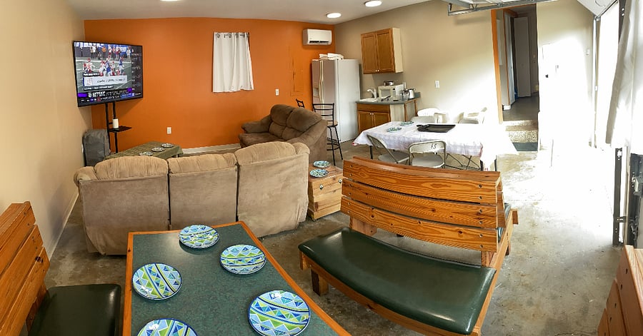 Indoor/Outdoor Entertainment Area with bar, table, fridge, couches, and 70" smart TV.