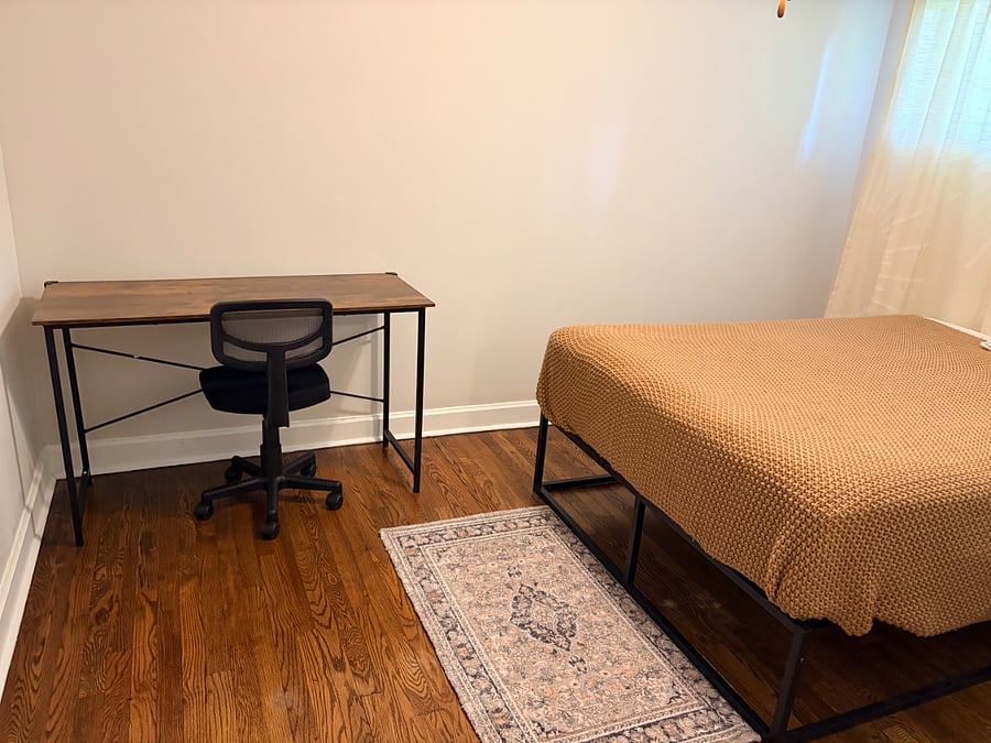 Bedroom with full sized bed, nightstand, lamp, rug, drawers, desk, chair, 2 storage baskets in closet, and laundry basket