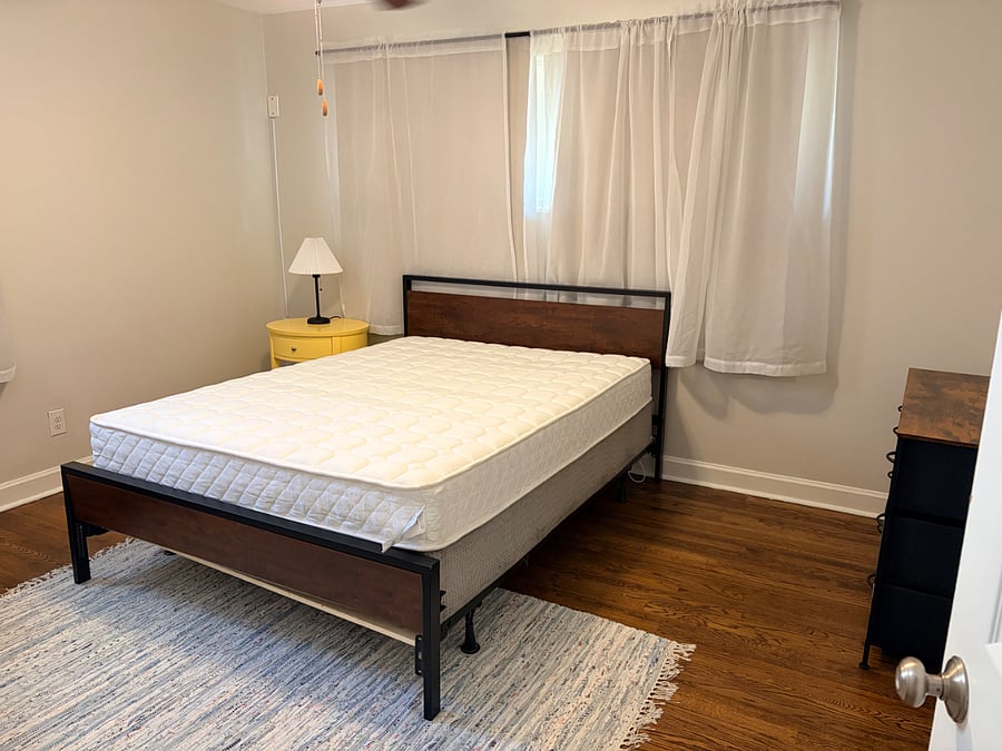 Bedroom with Queen sized bed, nightstand, lamp, rug, desk, chair,  and dresser