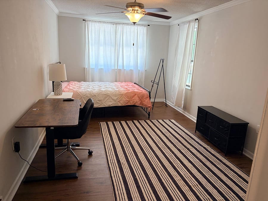 Private bedroom with Queen sized bed, dresser, desk, chair, nightstand, lamp, rug, and TV stand