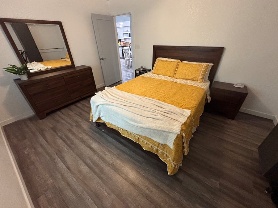 Bedroom 2 has a queen bed with closet, dressers and mounted smart TV.