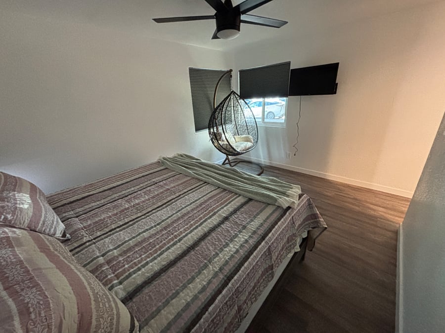Primary Bedroom has a king bed with closet, dressers, egg chair and mounted smart TV.