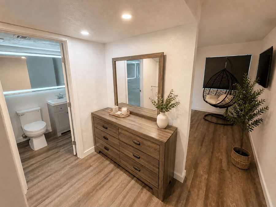 A serene view of the primary suite, with the private ensuite, generous dresser storage, and cozy egg chair creating a comfortable retreat to unwind and feel at home.