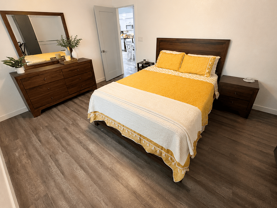A welcoming second bedroom with a queen bed, dresser storage, closet space, and a mounted smart TV.