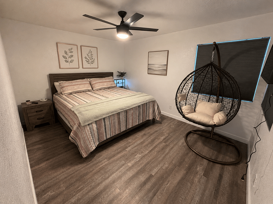 Unwind in the spacious primary bedroom with a king bed, generous storage, a cozy egg chair, and a mounted smart TV.