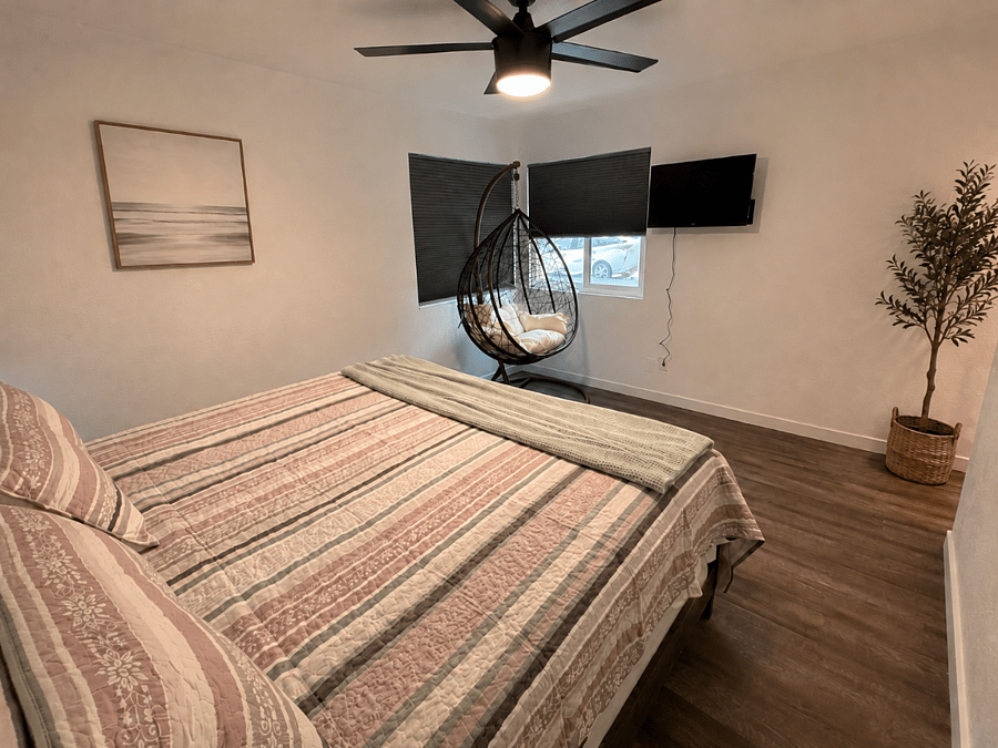 A peaceful second view of the primary bedroom, where the king bed, cozy reading chair and blackout blinds create an easy place to slow down, sleep deeply, and recharge.