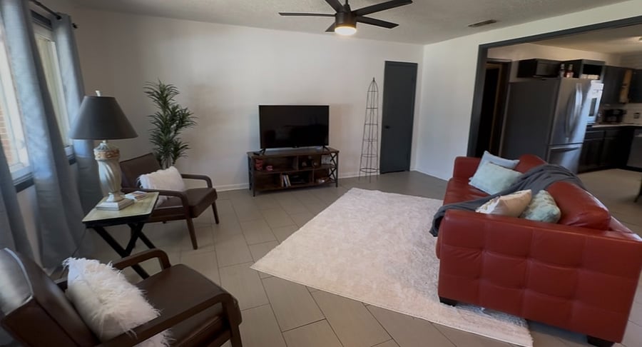 Relaxed Living Space  Stylish, Open & Ready to Unwind Kick back in a warm and welcoming living room featuring a rich deep red leather couch that adds character and comfort. A plush soft rug grounds the space, creating a cozy spot for lounging or stretching out after a long shift. Enjoy entertainment with a Roku-enabled TV and DVD player, ideal for winding down with your favorite series or films. The room offers an open layout, giving it an airy, easy-flow vibe thats perfect for hosting a guest or relaxing solo.