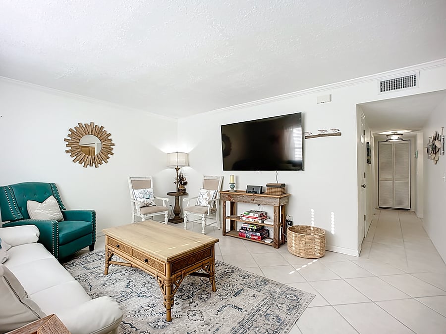 Living area with full size couch and extra chairs gives off that coastal vibe