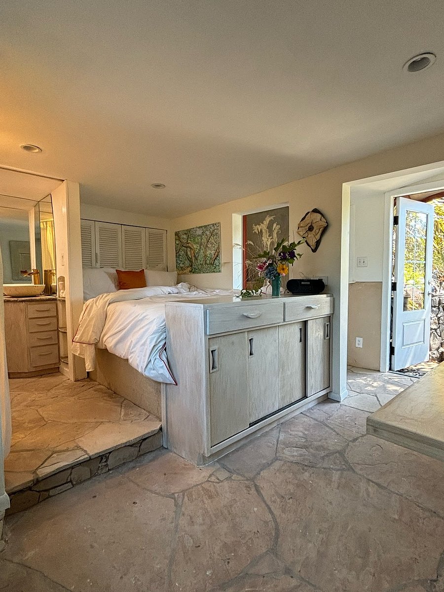 lower bedroom showing storage unit platform bed with louvered doors to large tv, and small 1/2 bathroom to the left