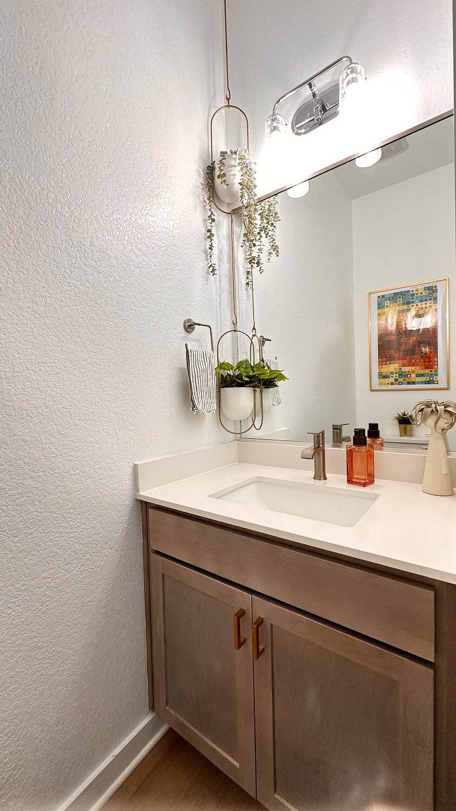 Half bath on the main floor features simple modern decor and efficient tilt-away storage for discreetly stashing personal hygiene products.