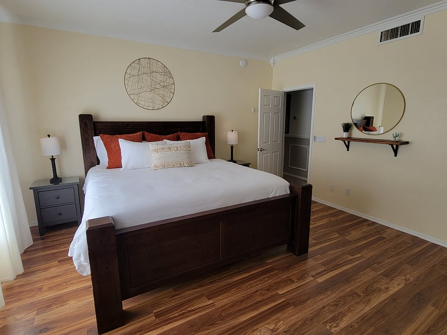 Primary bedroom with king size bed, dresser, walk in closet, two end tables and recliner chair. 