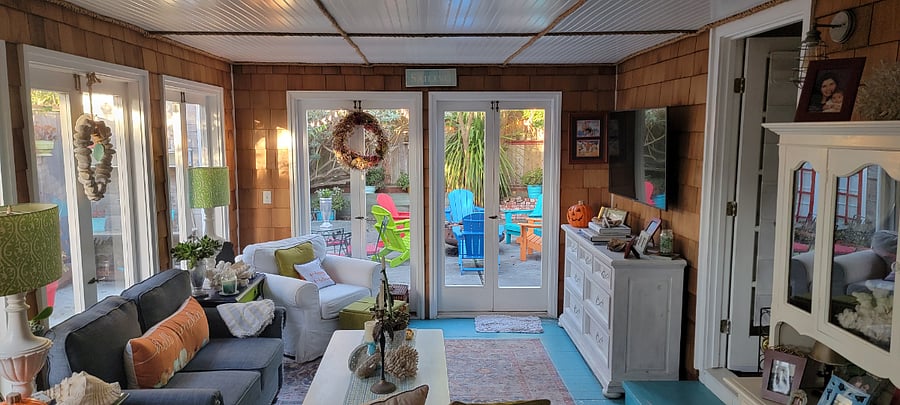 The sunroom serves a s relaxing family room with a large wall-mounted TV, You overlook the plethora of hummingbirds in the back courtyard, as well as cafe lights and a firepit.