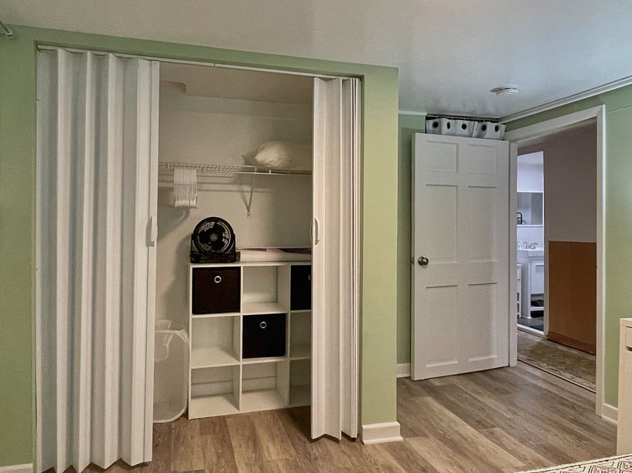 Open shelf and drawer clothes storage, hamper, extra linens, and fan.