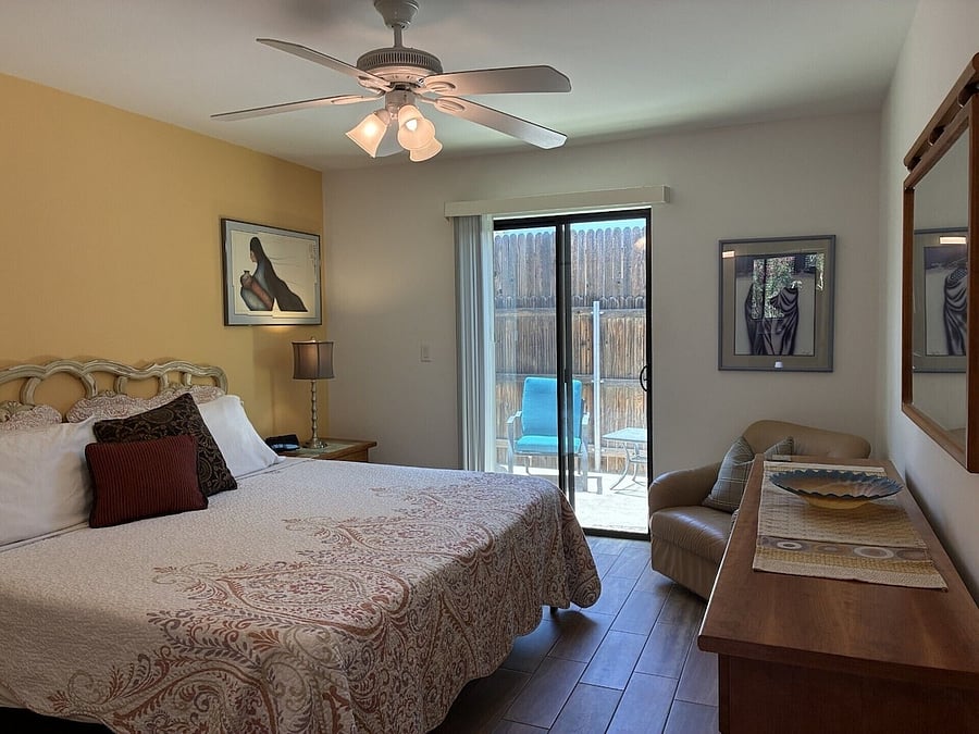 Bedroom with sliding glass door leading to fenced in backyard.
