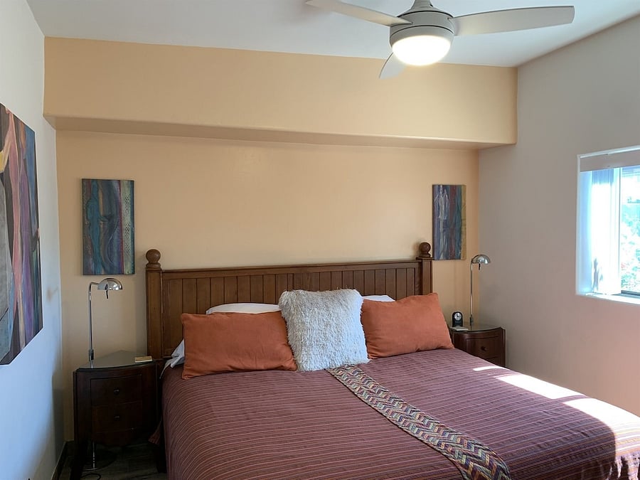 Bedroom with king bed, and window that views walled in back yard.
