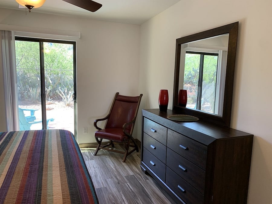 Bedroom with sliding glass door leading to fenced backyard.