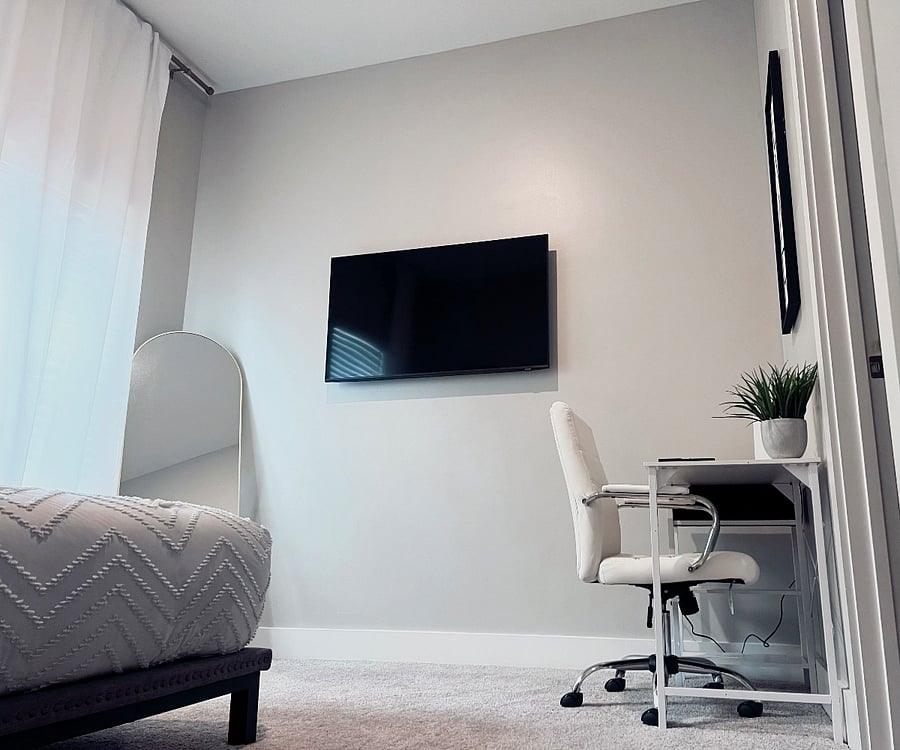 Comfortable daybed, mounted TV, and a dedicated desk area for remote work or study.