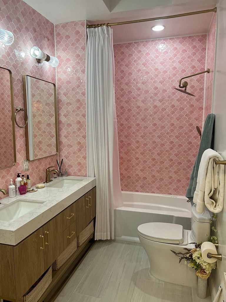 Spa-like bathroom with a double-sink vanity, brass fixtures, playful pink tile, and a skylight that fills the space with beautiful natural light.