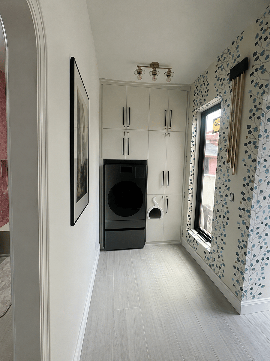 Dedicated laundry area with a sleek, energy-efficient washer/dryer, extensive custom floor-to-ceiling cabinetry, and a charming built-in cat hideaway.