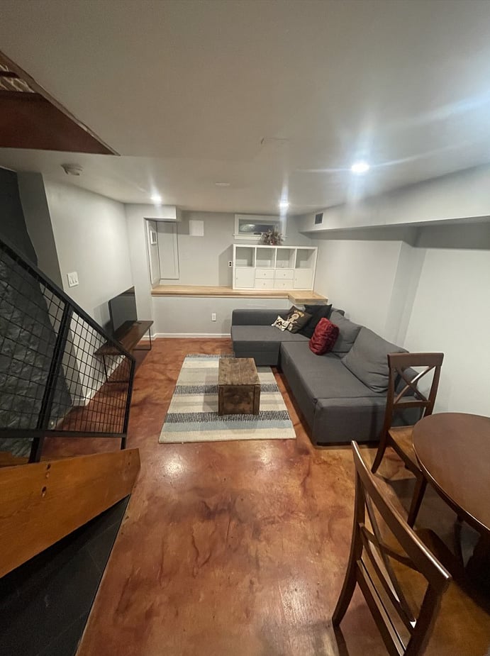 Basement has a fold out couch and television, space for storage and a work bench for crafting, table space for work-from-home