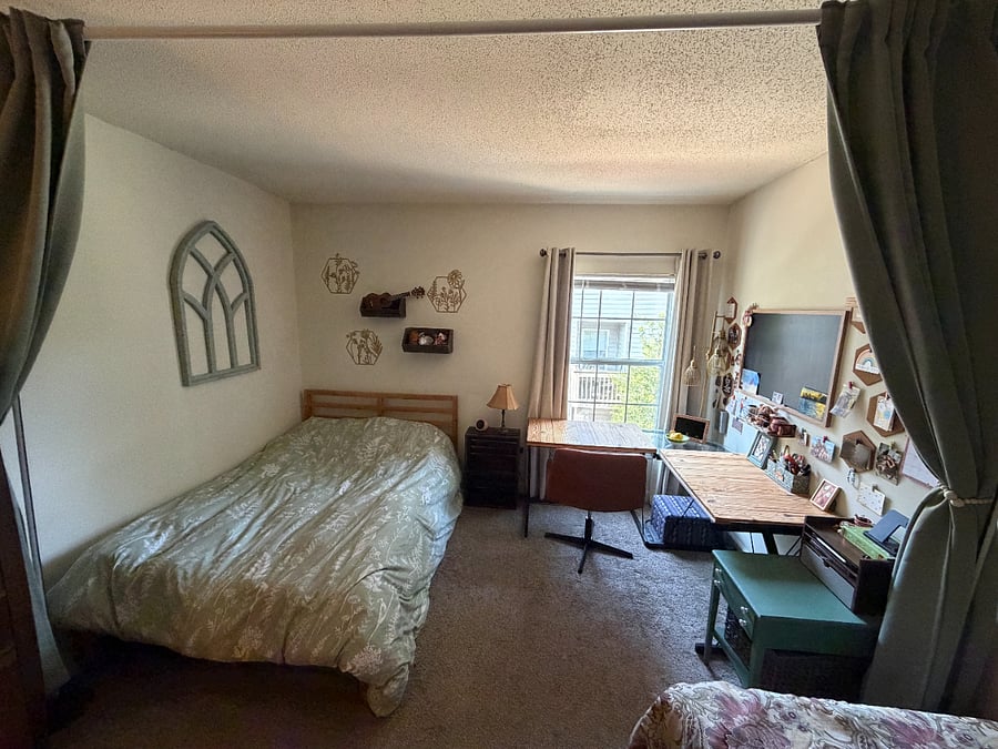 Half of the room has a full-size bed with a window facing a desk.