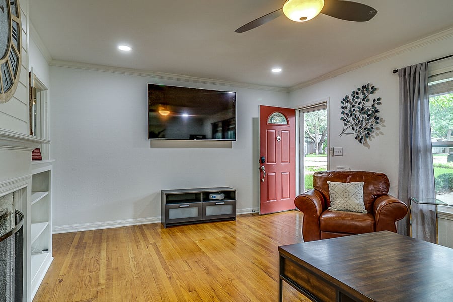 Entry area inside front door with large smart TV, leather furniture and fireplace. Restored original wood flooring throughout home plus tile kitchen and bath