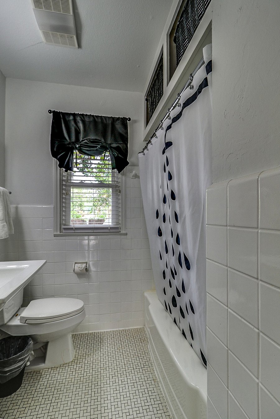 Fully tiled large bathroom with shower/tub combo, sink and cabinets.