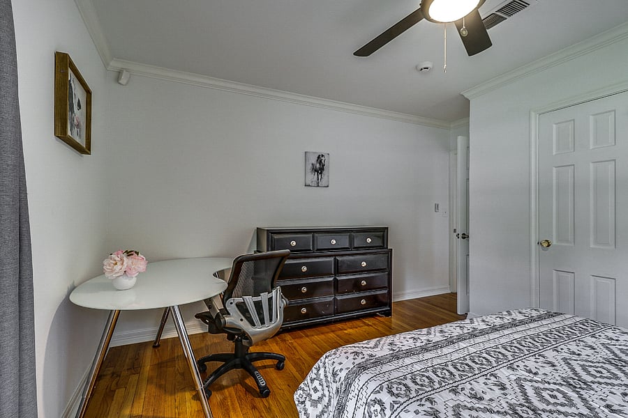 Second bedroom has a queen bed with closet, fan and large executive desk plus dresser, side tables and lamps