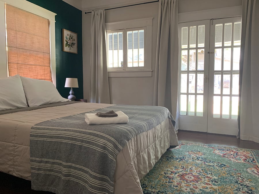 A queen bed in the master bedroom with working French doors that open to the front porch.