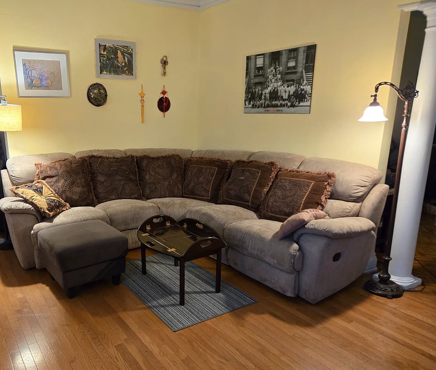 Living room has comfy sectional couch with recliner seats, exercise bike and free weights, shelves and hardwood floors, lots of natural light. Big monitor for your streaming.