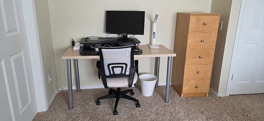 Workspace with standing desk, external monitor, peripherals, comfy chair, and ample storage