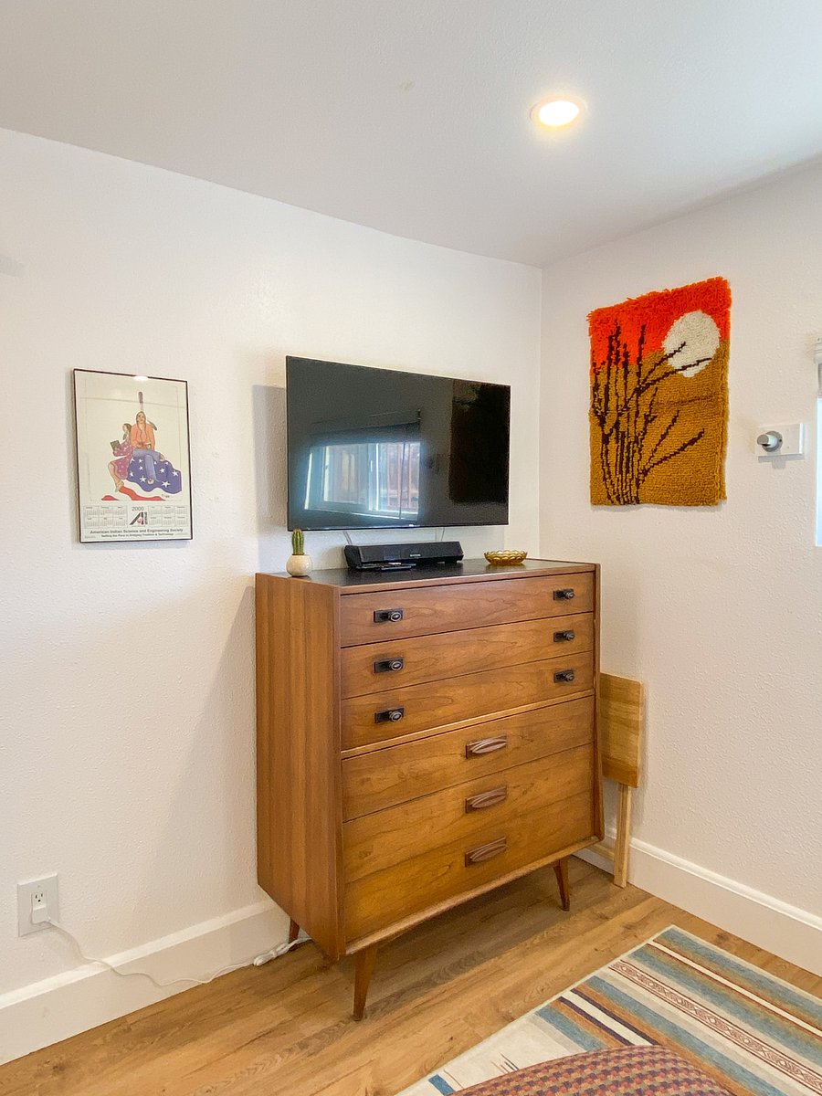 Smart TV with sound bar that sits on a vintage dresser.