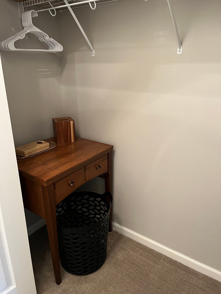 Large clean closet with closing doors, hangers, ironing, convenience table, laundry hamper, and extra linens.W