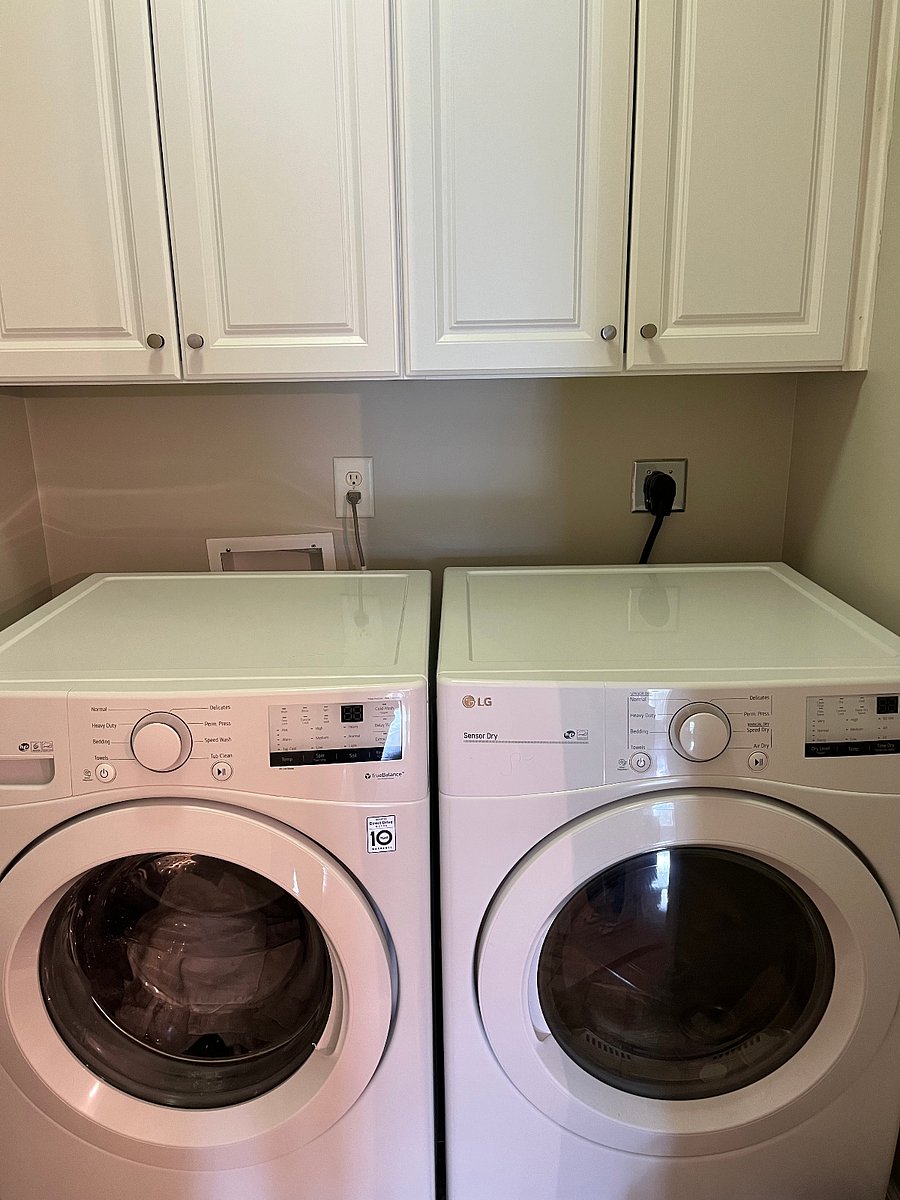 washer/dryer and extra storage in laundry room with door to reduce sound.