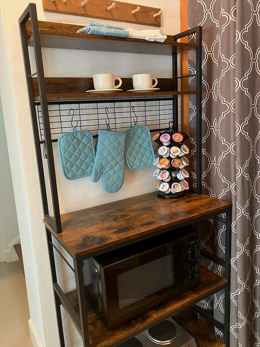 Bakers rack with microwave and stove top in kitchenette