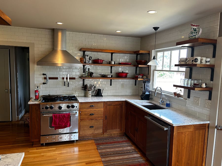 Professional gas range and hood, open shelving, Miele dishwasher. Kitchen window looks into the backyard.Fu