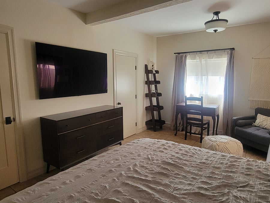 Bedroom with dresser, 65" TV, desk and chair