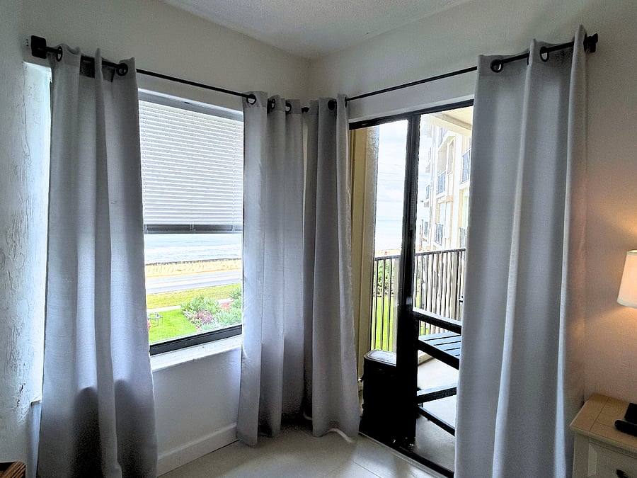 Bedroom 1 features a king-sized bed, beachfront views, a TV, a ceiling fan, a desk,  and access to the balcony. 