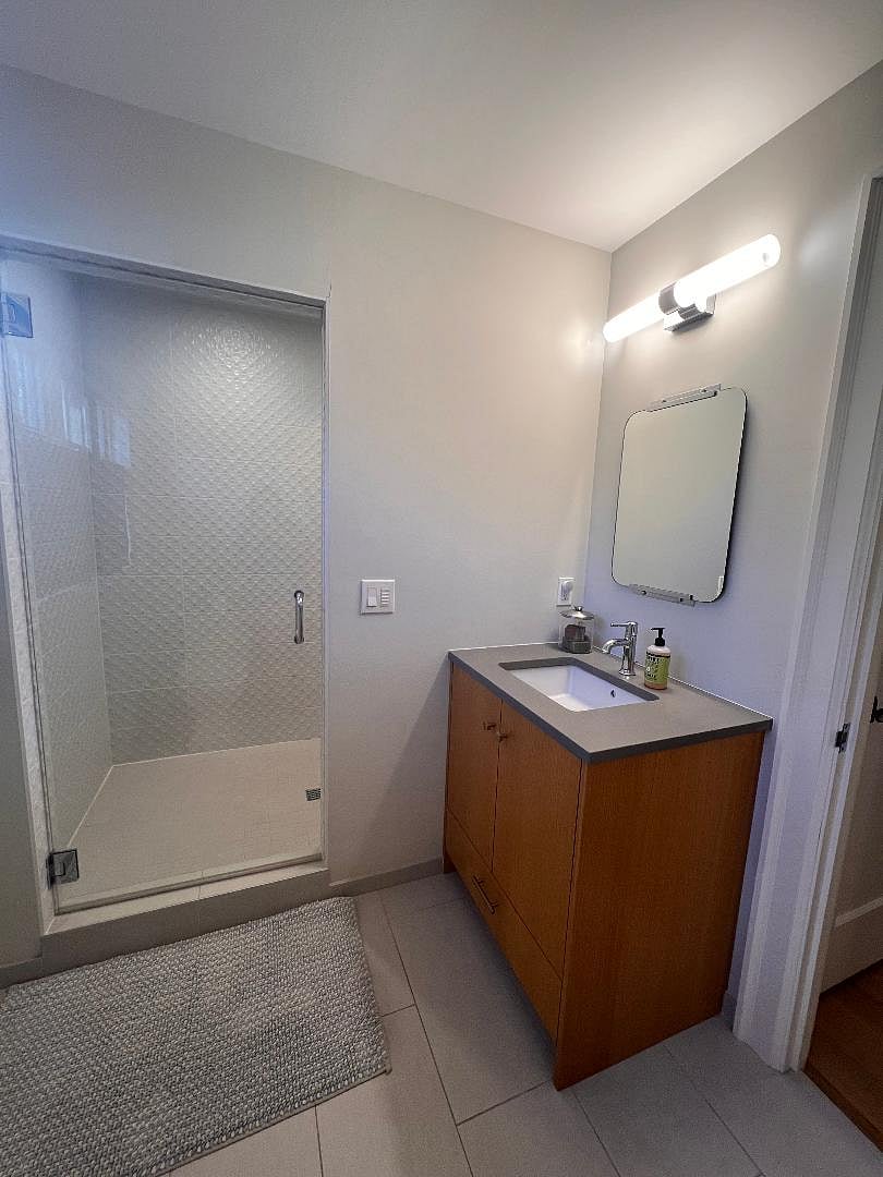 Bathroom includes large mirror, walk-in shower and sink in addition to toilet.