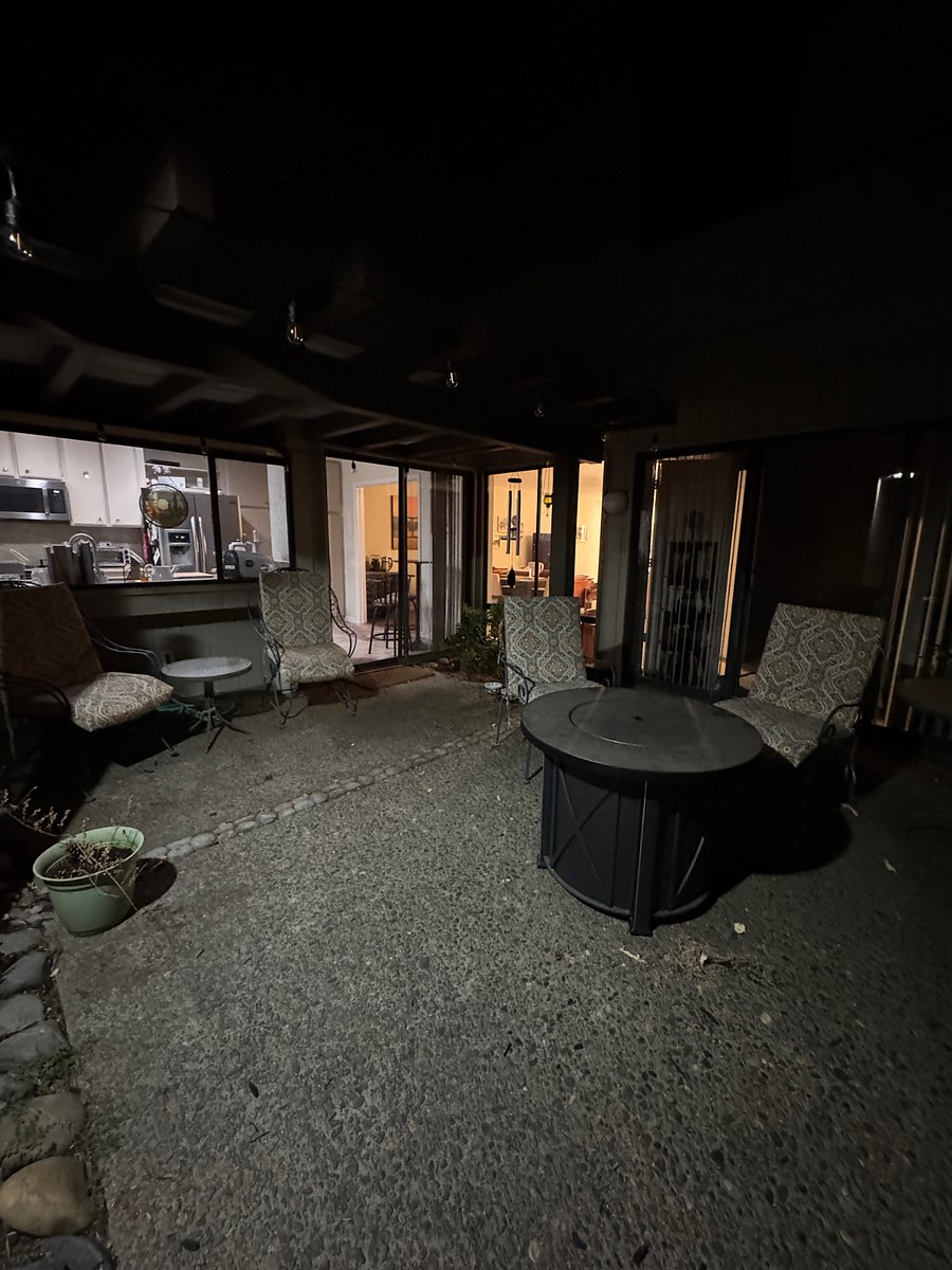 Outdoor courtyard has twinkle lights, umbrella table and propane firepit