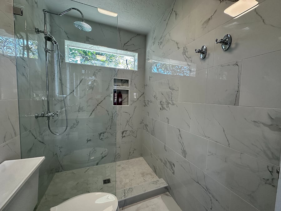 Wall-to-ceiling tile with rainfall shower, daylight window.