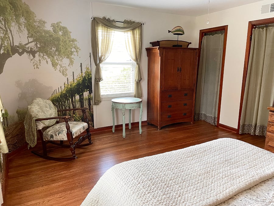 Green bedroom. Rocking chair beside wall mural.
