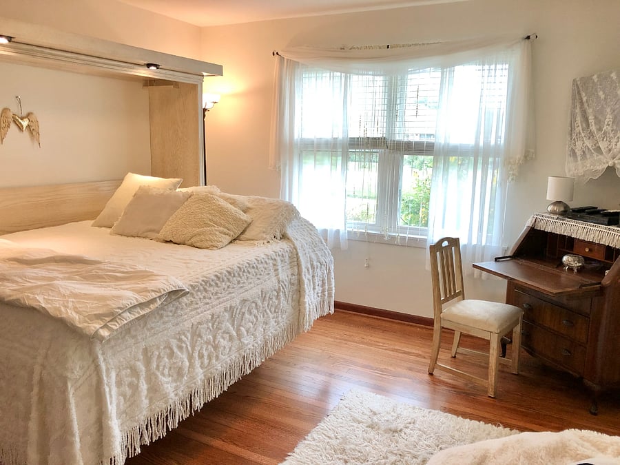 White bedroom, with desk and TV in corner.