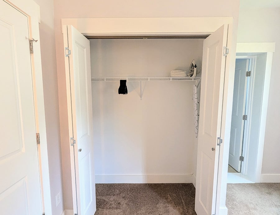 Large closet with hangers, iron and ironing board.