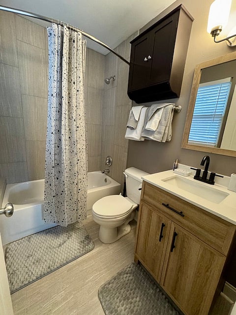 Fully renovated bathroom includes ceramic tile flooring and porcelain tile around the tub/shower