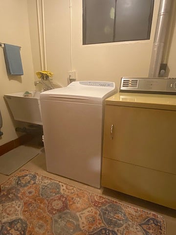Utility room with washer, dryer, laundry tub, drying rack, iron & ironing board, vacuum and other cleaning supplies