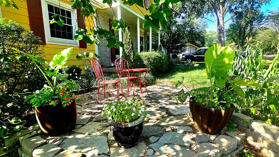 Charming garden patio with red bistro set perfect for morning coffee or evening relaxation.